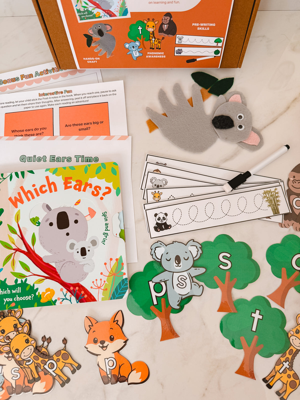 Educational materials for children including a book, cards, and foam animals on a wooden surface.