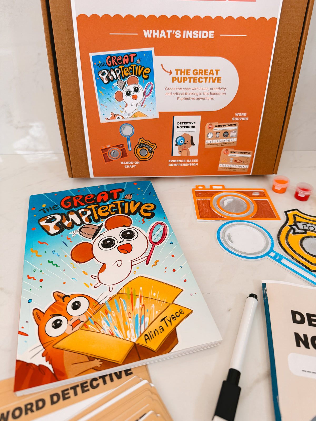 Children's educational game box titled 'The Great Pupective' with accessories on a white surface.