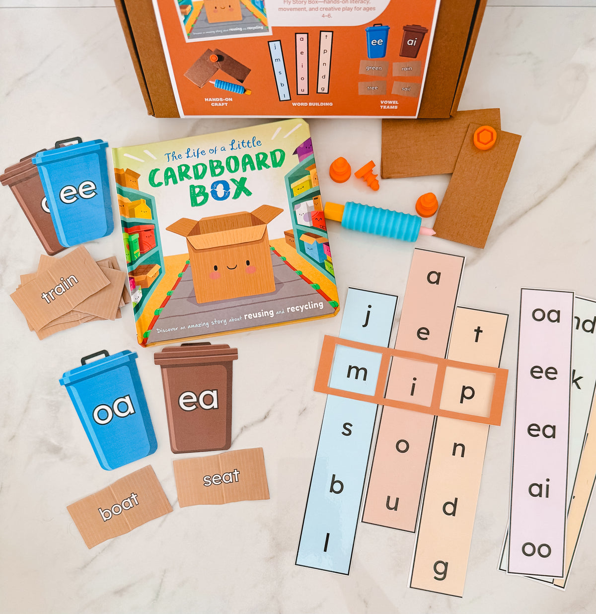 Educational materials for learning phonics with word cards and a book titled 'The Life of a Little Cardboard Box'.