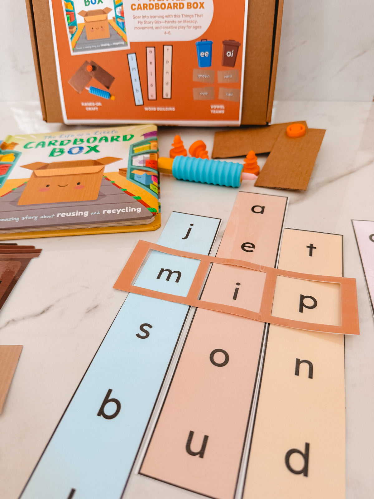 Educational children's toy with letter tiles and a cardboard box packaging on a marble surface.